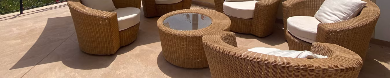 Uitnodigende zithoek met vijf rieten stoelen en ronde glazen tafel op terras met parasol en groene natuur vakantiewoning son vida